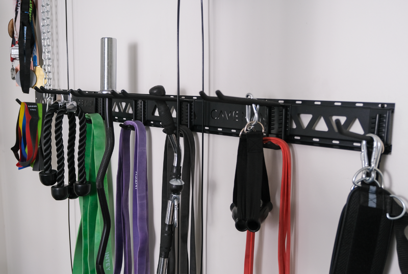 Load image into Gallery viewer, Wall-mounted metal rack with various exercise equipment and accessories on a white wall.
