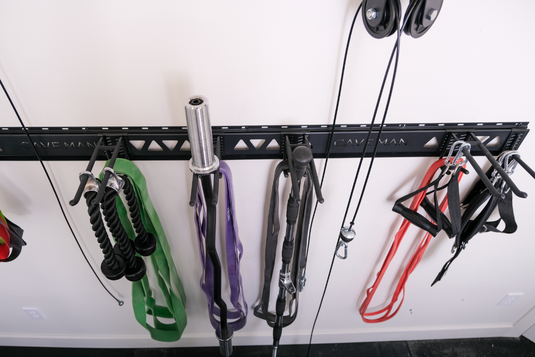 Gym equipment including resistance bands and cables hanging on a wall-mounted rack.